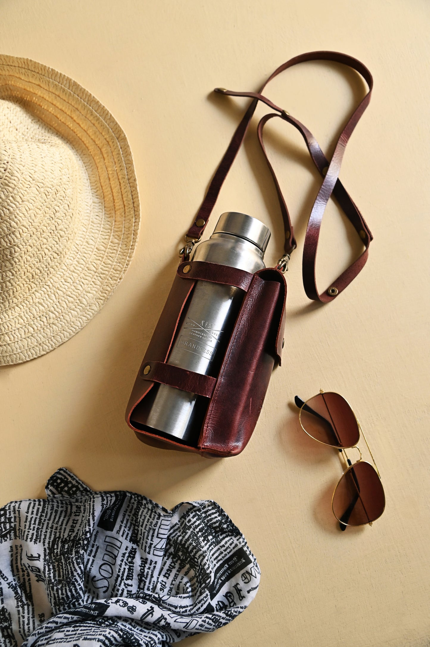 Burgundy handcrafted leather bottle case with utility pocket and steel flask, worn crossbody