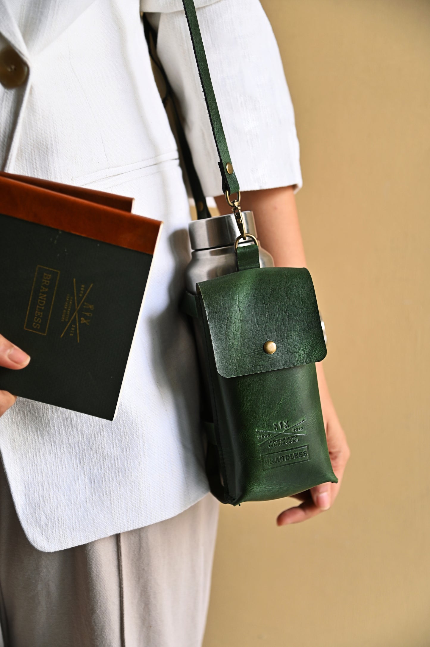 Dark Green handcrafted leather bottle case with utility pocket and steel flask, worn crossbody