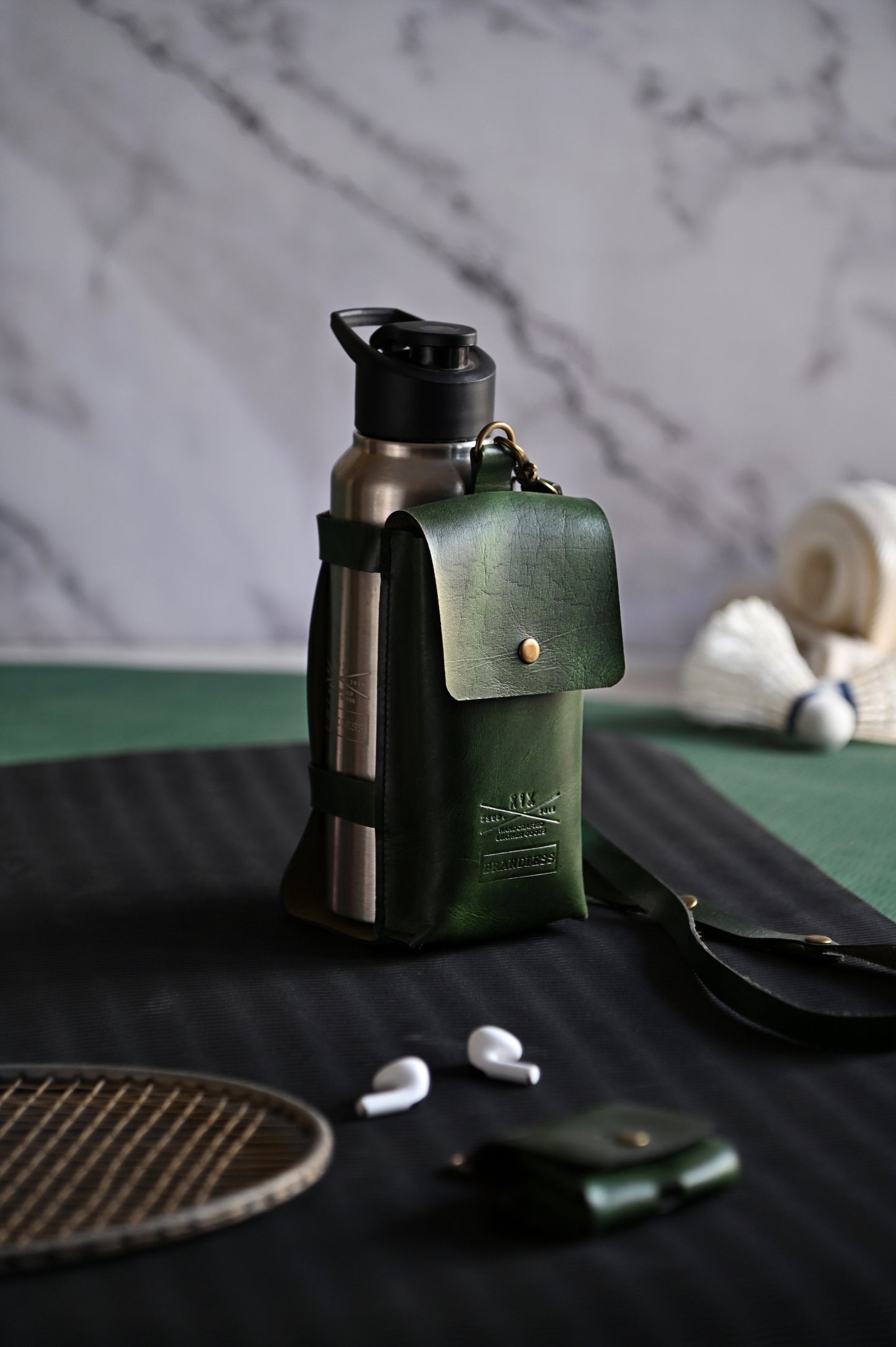 Dark Green handcrafted leather bottle case with utility pocket and steel flask, worn crossbody