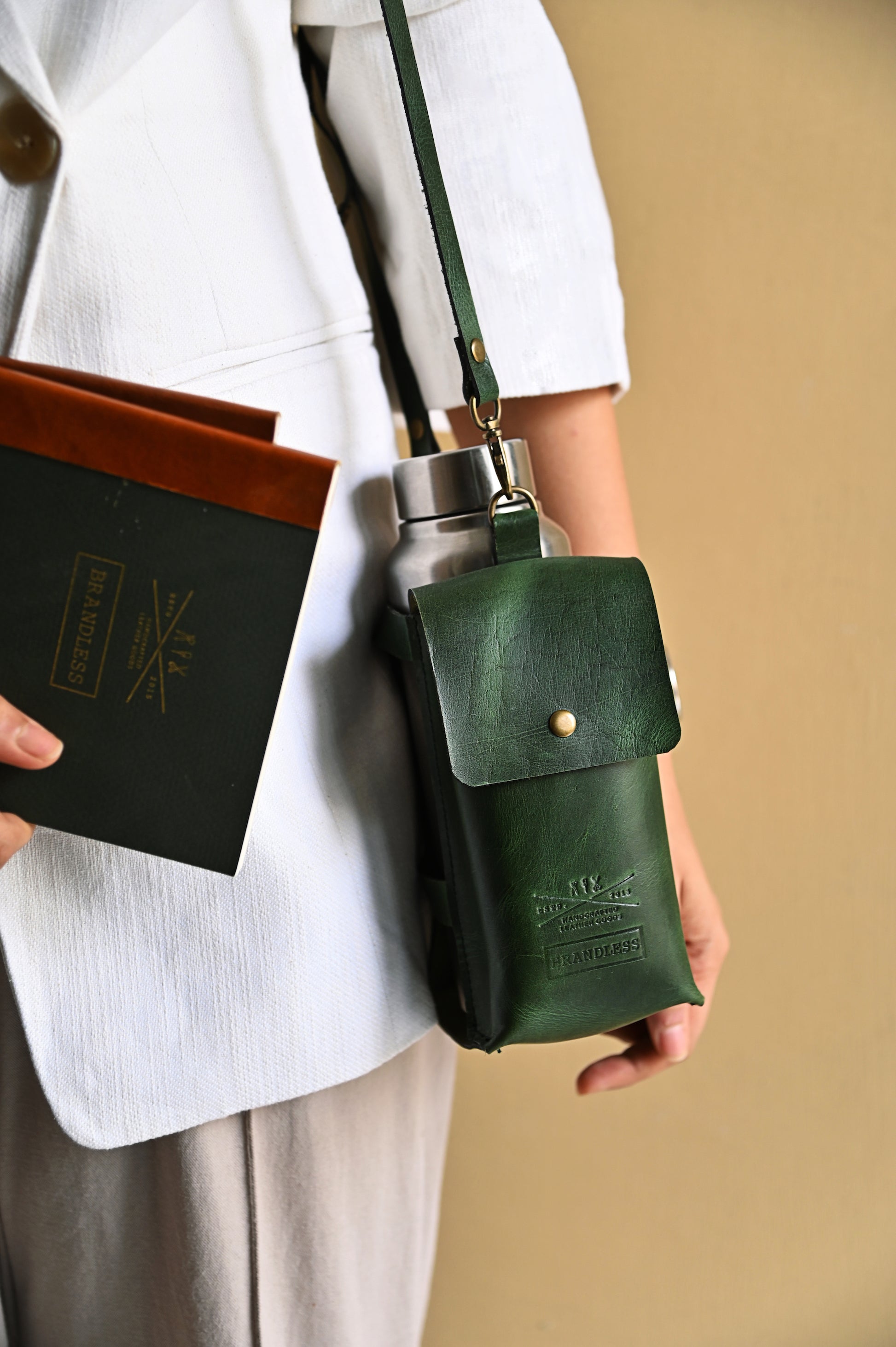 Dark Green handcrafted leather bottle case with utility pocket and steel flask, worn crossbody