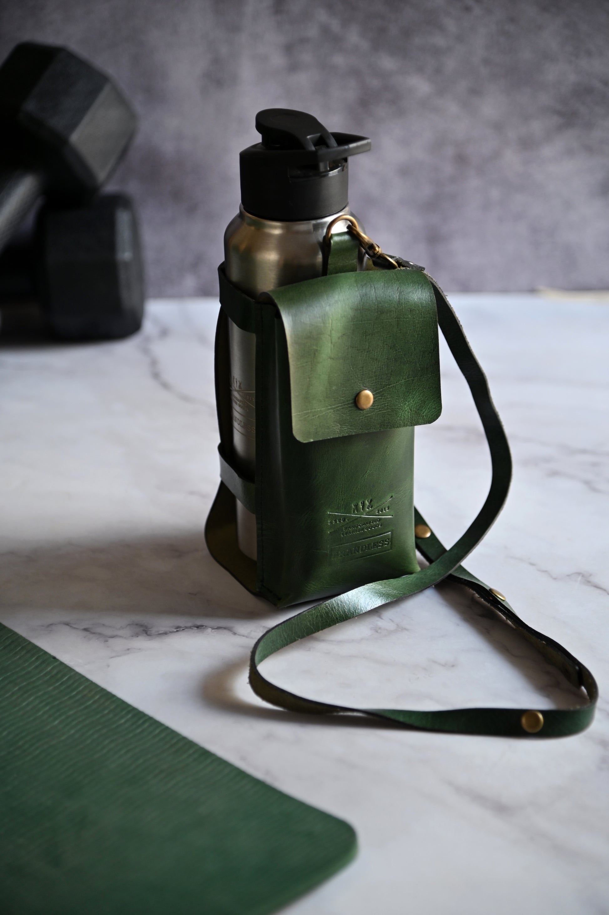 Dark Green handcrafted leather bottle case with utility pocket and steel flask, worn crossbody